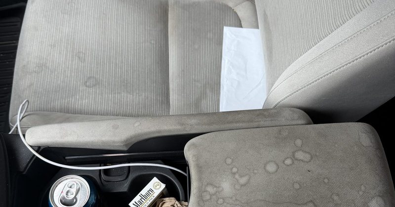 Cloth seats and centre armrest before any work — stains, litter and an empty can