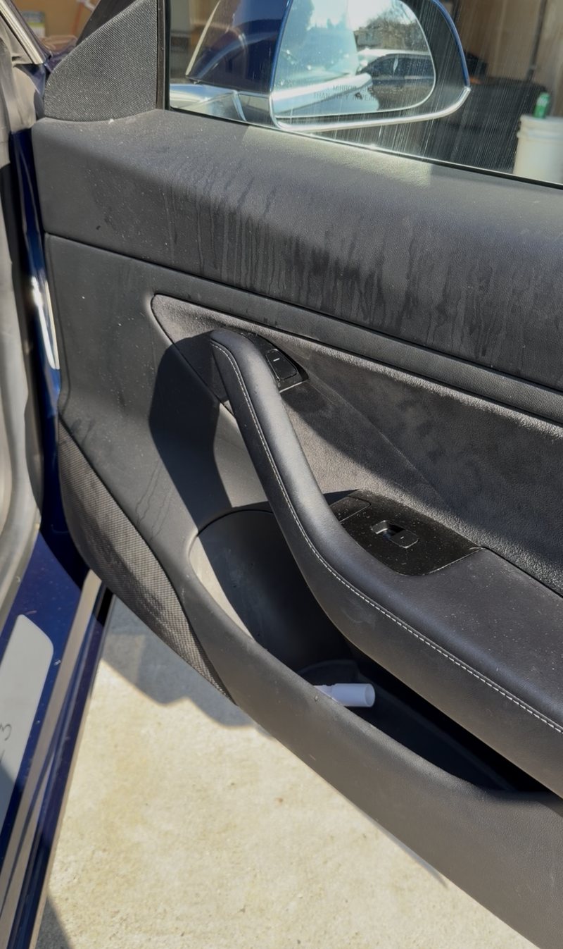 Tesla front door card before cleaning — dust and dried streaks across the trim and alcantara insert