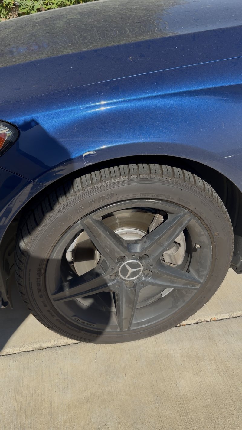 Mercedes AMG wheel and blue front wing before cleaning — brake dust on the spokes and flat, dusty paint
